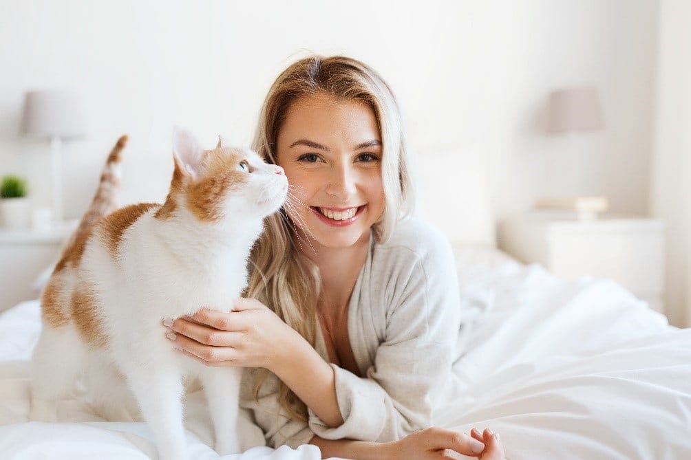 Cat and woman smile on bed
